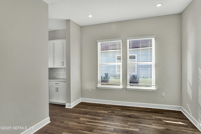 unfurnished room with recessed lighting, dark wood-style flooring, and baseboards