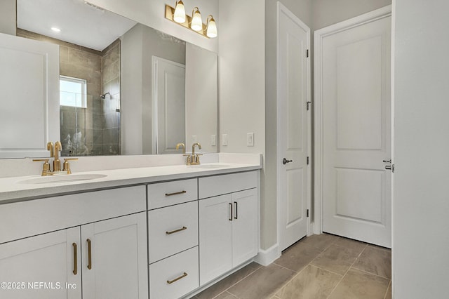 bathroom with tiled shower, a sink, and double vanity