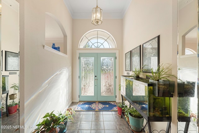 tiled foyer with a chandelier, a towering ceiling, crown molding, and french doors