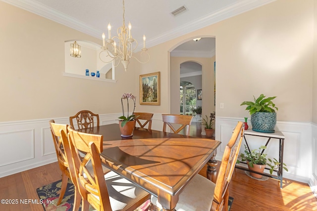 dining space featuring crown molding, wood-type flooring, and a notable chandelier