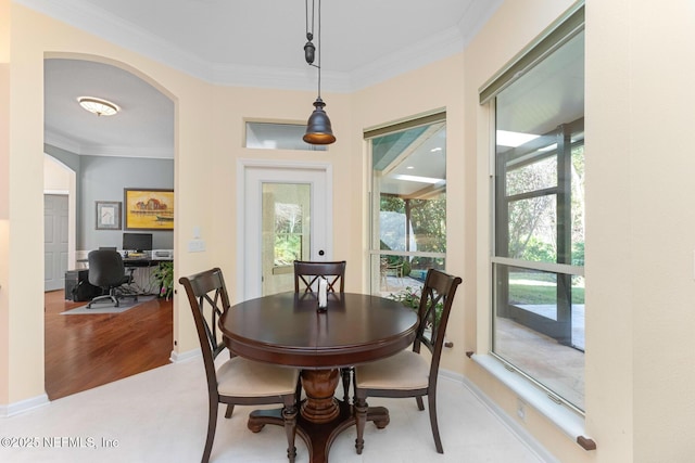 dining space with light wood-type flooring, crown molding, and a wealth of natural light