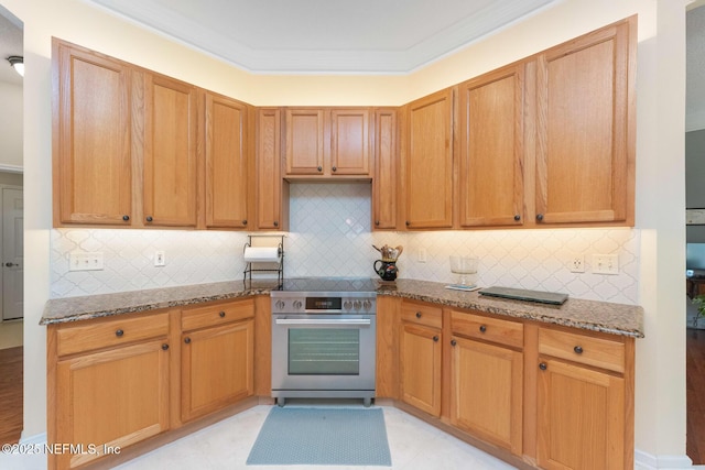 kitchen with light stone countertops, backsplash, high end stove, crown molding, and light tile patterned flooring