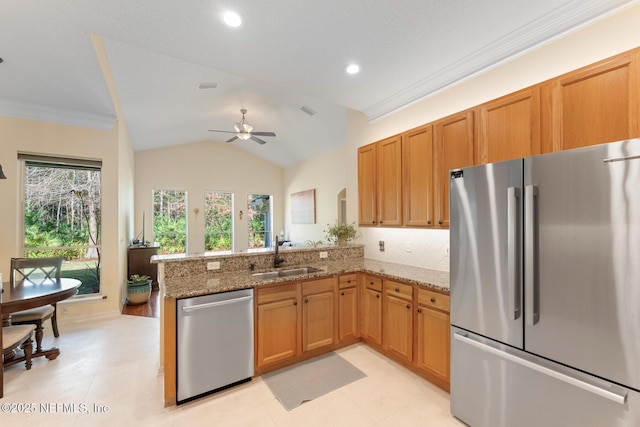 kitchen with sink, vaulted ceiling, ceiling fan, appliances with stainless steel finishes, and kitchen peninsula