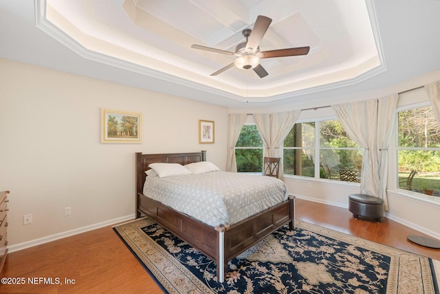 bedroom with a tray ceiling, ceiling fan, and wood-type flooring