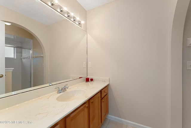 bathroom featuring tile patterned flooring, vanity, and a shower with door