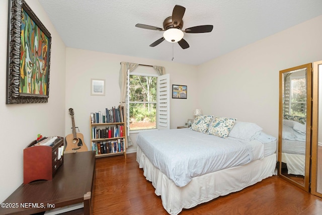 bedroom featuring a textured ceiling, ceiling fan, and dark wood-type flooring