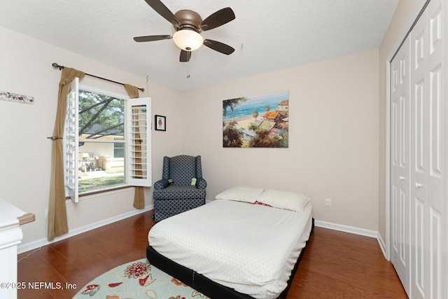 bedroom with ceiling fan, a closet, dark wood-type flooring, and a textured ceiling