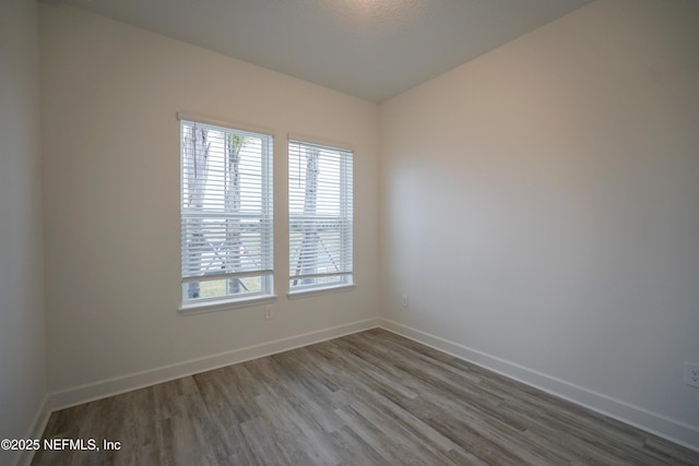 unfurnished room with a healthy amount of sunlight, baseboards, and wood finished floors