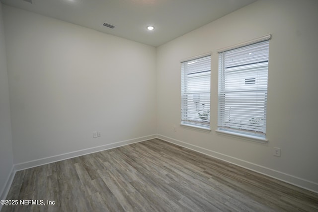 spare room with recessed lighting, wood finished floors, visible vents, and baseboards