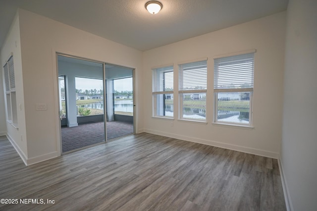 empty room with a textured ceiling, baseboards, and wood finished floors