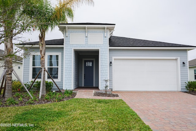 view of front of home with a garage, a front lawn, and decorative driveway