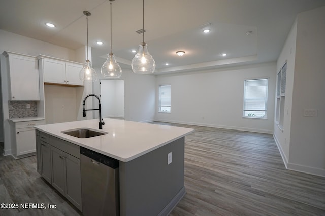 kitchen with a raised ceiling, light countertops, visible vents, stainless steel dishwasher, and a sink