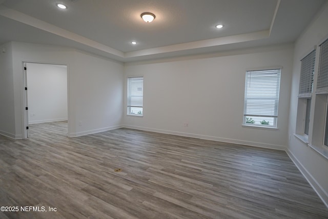 unfurnished room with baseboards, a tray ceiling, and wood finished floors