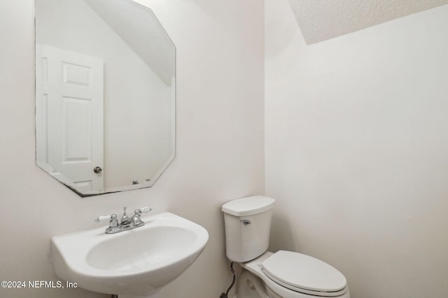 bathroom with a textured ceiling, toilet, and sink