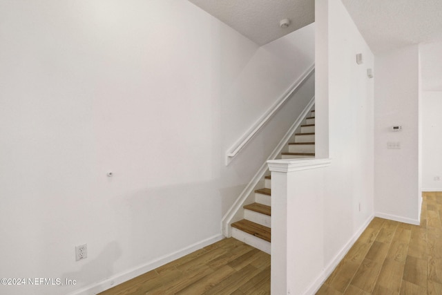 stairway featuring wood-type flooring and a textured ceiling