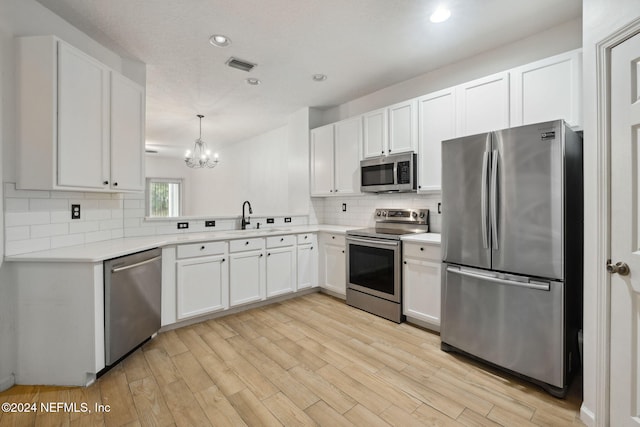 kitchen with pendant lighting, white cabinets, sink, tasteful backsplash, and stainless steel appliances