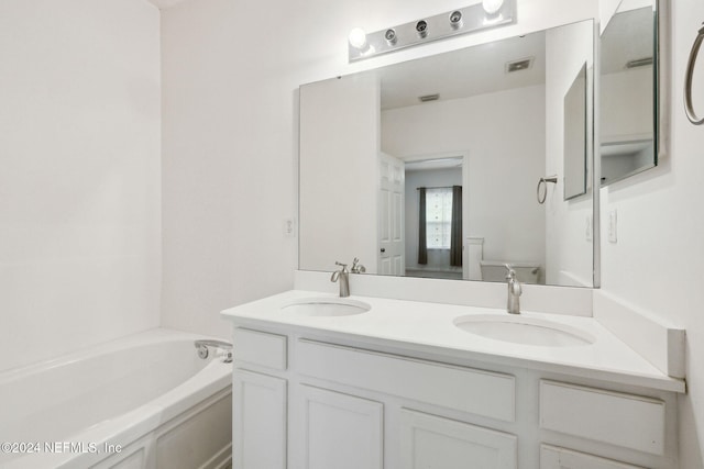 bathroom with vanity, a bath, and toilet