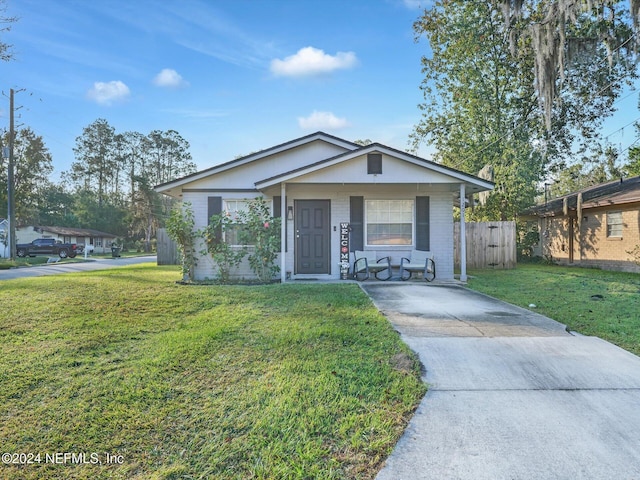 ranch-style home featuring a front lawn and covered porch