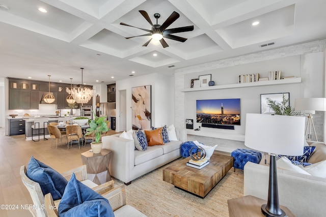 living room featuring ceiling fan with notable chandelier, beamed ceiling, coffered ceiling, and light wood-type flooring