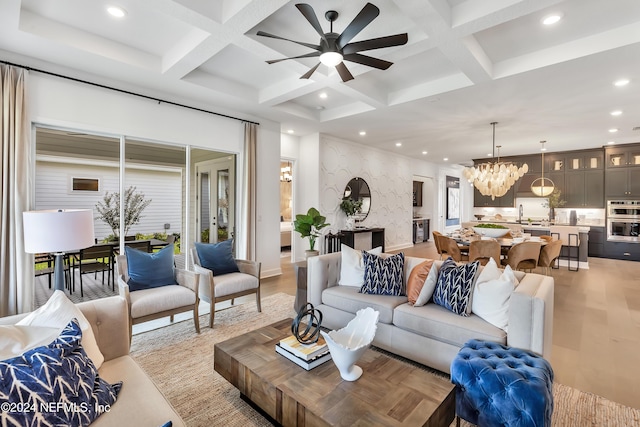 living room with beamed ceiling, light hardwood / wood-style flooring, ceiling fan with notable chandelier, and coffered ceiling