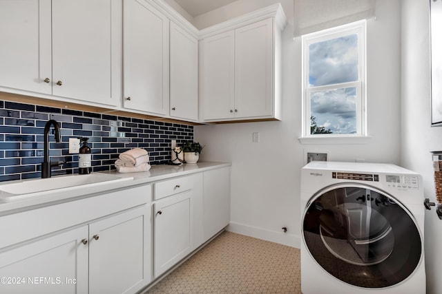 washroom featuring cabinet space, baseboards, washer / clothes dryer, and a sink