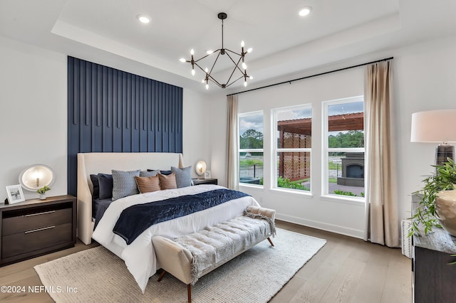 bedroom featuring light wood-type flooring, baseboards, a tray ceiling, and recessed lighting