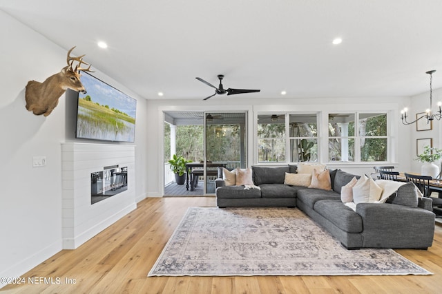 living room featuring light hardwood / wood-style floors and ceiling fan with notable chandelier