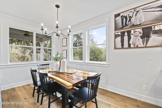 dining space with light hardwood / wood-style floors and an inviting chandelier