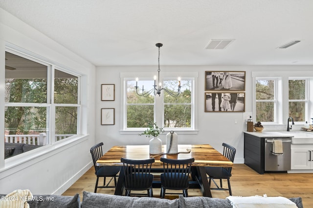 dining room featuring a notable chandelier, light hardwood / wood-style flooring, and sink