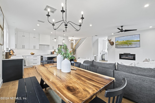 dining area featuring sink, ceiling fan with notable chandelier, and light hardwood / wood-style flooring