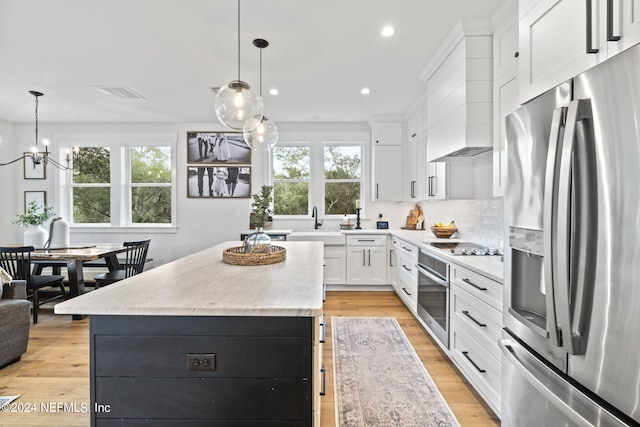 kitchen with a kitchen island, stainless steel appliances, decorative light fixtures, and white cabinets