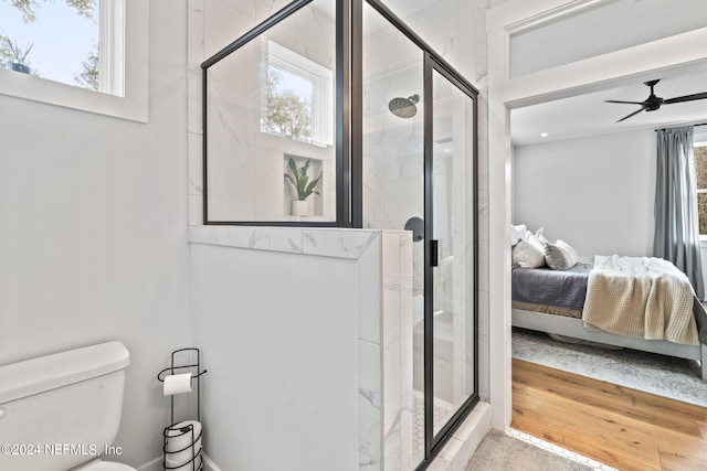 bathroom featuring toilet, an enclosed shower, ceiling fan, and a wealth of natural light