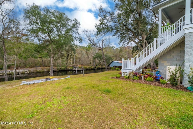 view of yard featuring ceiling fan and a water view