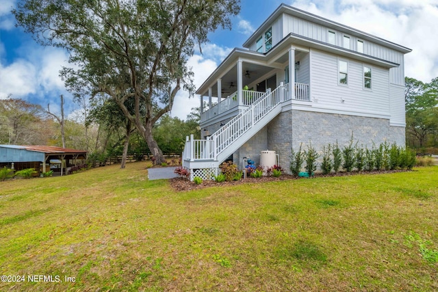 back of house with covered porch, ceiling fan, and a lawn