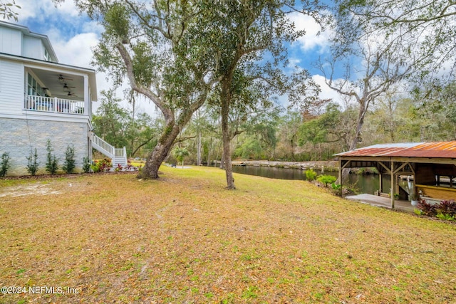 view of yard featuring ceiling fan and a water view