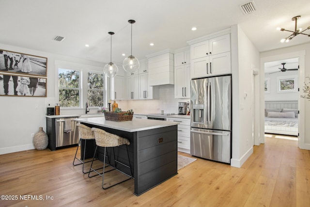 kitchen featuring a kitchen island, appliances with stainless steel finishes, pendant lighting, and white cabinetry