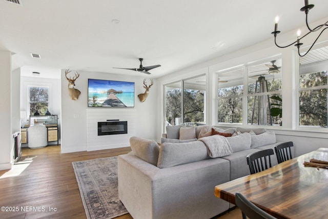 living room featuring ceiling fan with notable chandelier and wood-type flooring