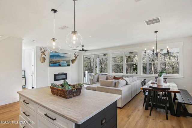 kitchen with hanging light fixtures, white cabinetry, a center island, and ceiling fan with notable chandelier