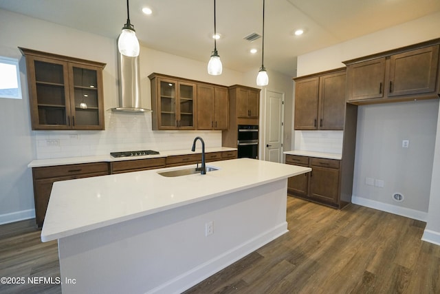 kitchen with black gas cooktop, wall chimney range hood, sink, decorative backsplash, and decorative light fixtures