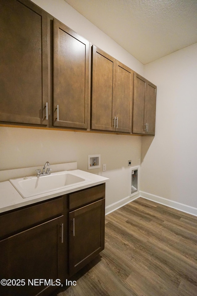 washroom featuring hookup for an electric dryer, washer hookup, a sink, cabinet space, and dark wood finished floors