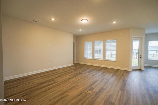 unfurnished room with dark wood-style flooring, recessed lighting, visible vents, and baseboards