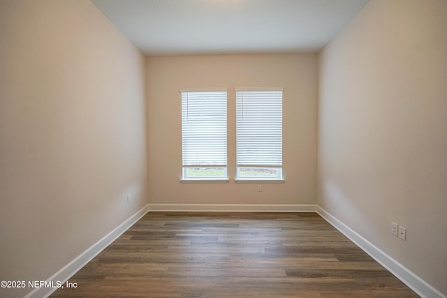 empty room with baseboards and dark wood-type flooring