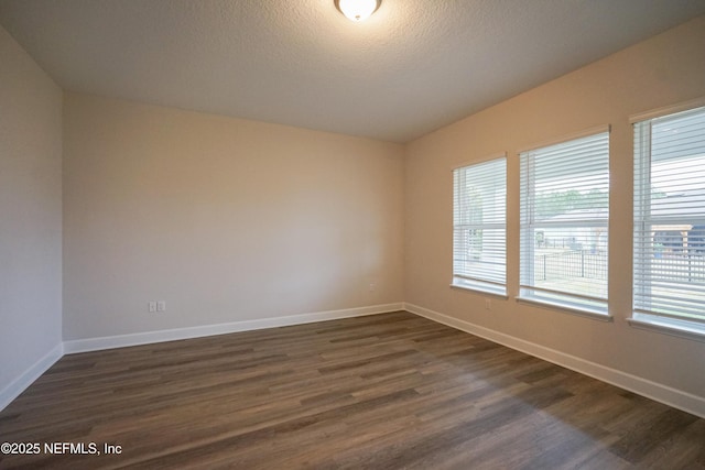 empty room featuring a textured ceiling and dark hardwood / wood-style floors