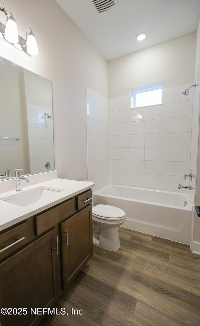 full bathroom with toilet, wood finished floors, vanity, visible vents, and shower / washtub combination