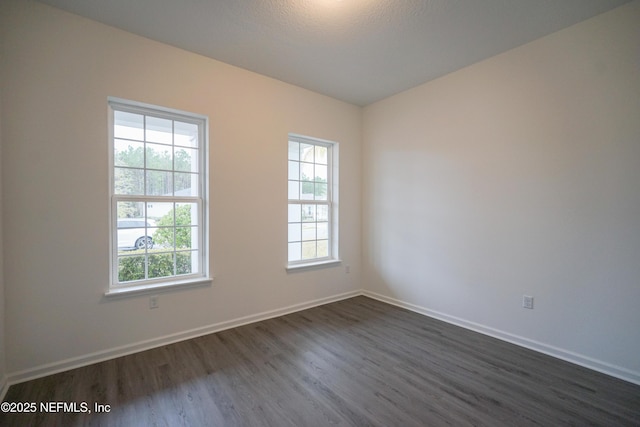 spare room with a textured ceiling and dark hardwood / wood-style floors