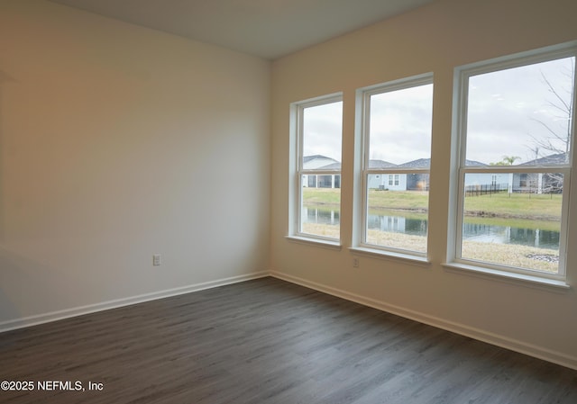 empty room with a water view and dark hardwood / wood-style floors