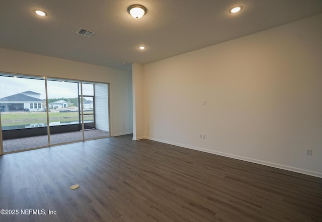 unfurnished room with a textured ceiling and dark wood-type flooring