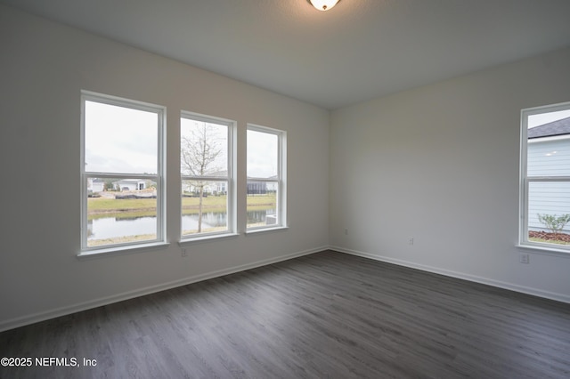 empty room featuring a water view and dark wood-type flooring