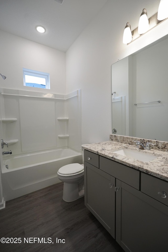 full bathroom featuring toilet, hardwood / wood-style floors, vanity, and tub / shower combination