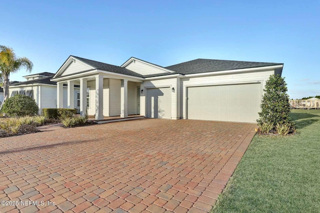 view of front of property with decorative driveway, an attached garage, and a front yard